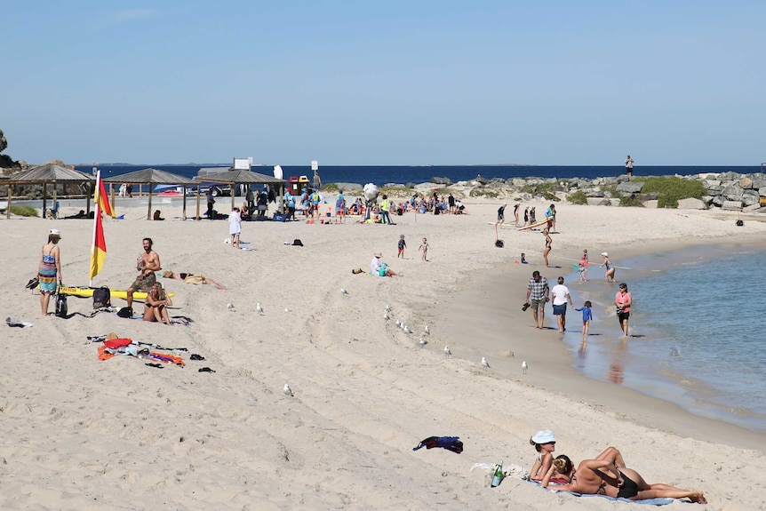 People lie on the sand at Cottesloe Beach.