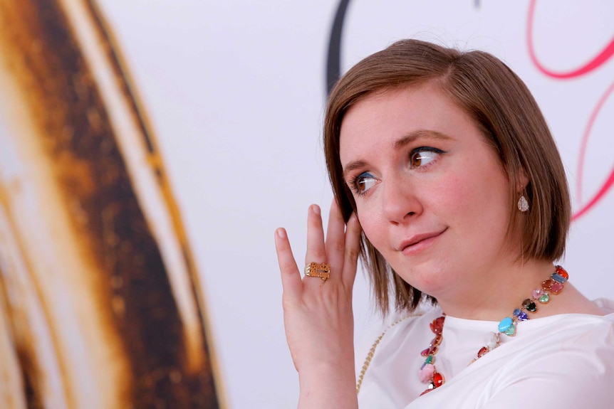 Lena Dunham brushes her hair off her face