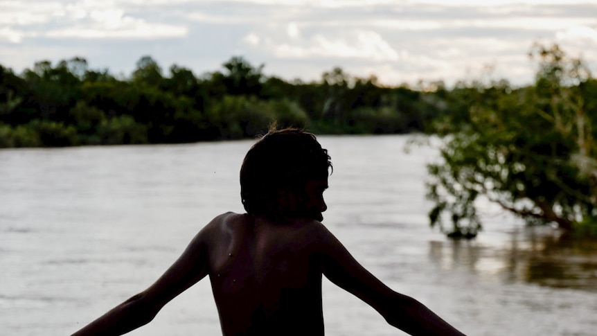 a young boy in front of a creek