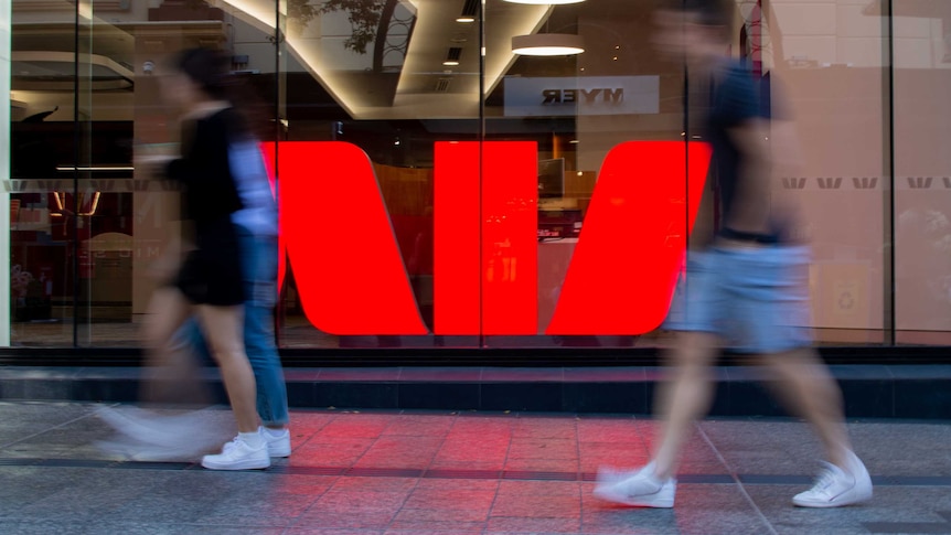 People walking past a Westpac sign.