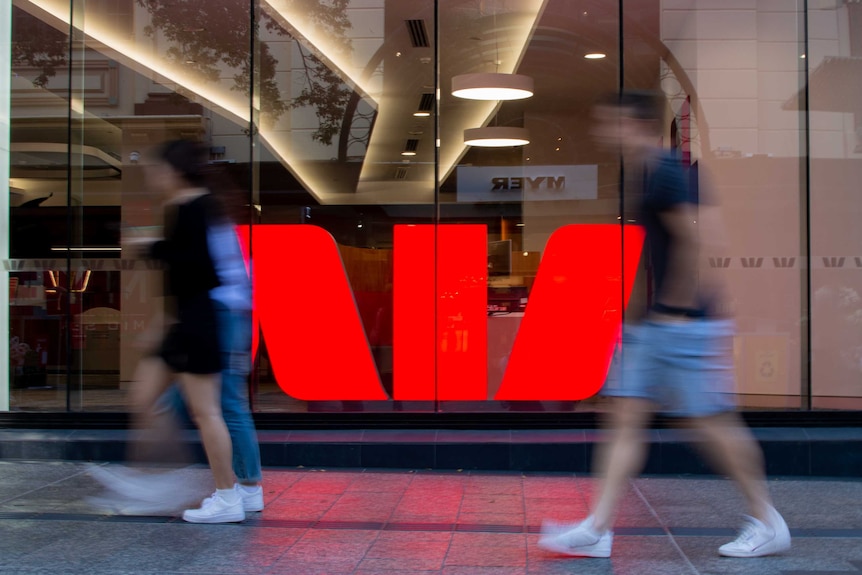 People walking past a Westpac sign.