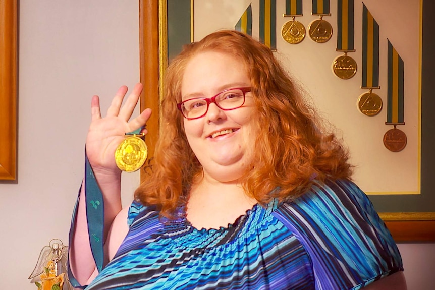 Siobhan paton holds up a gold medal and smiles.