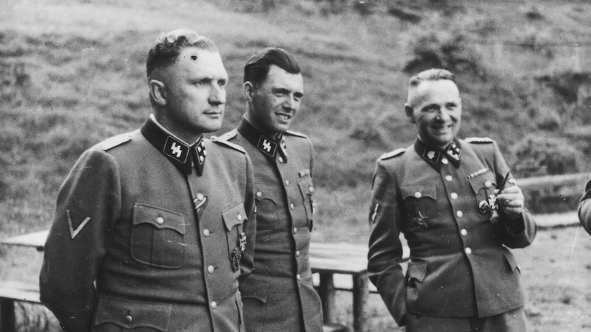 Nazi physician Josef Mengele (centre) stands between two SS officers.