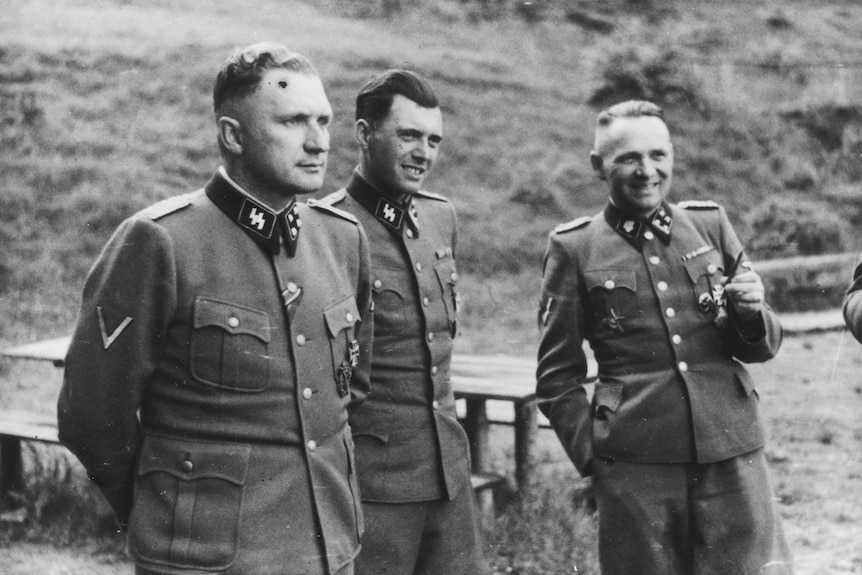 Nazi physician Josef Mengele (centre) stands between two SS officers.