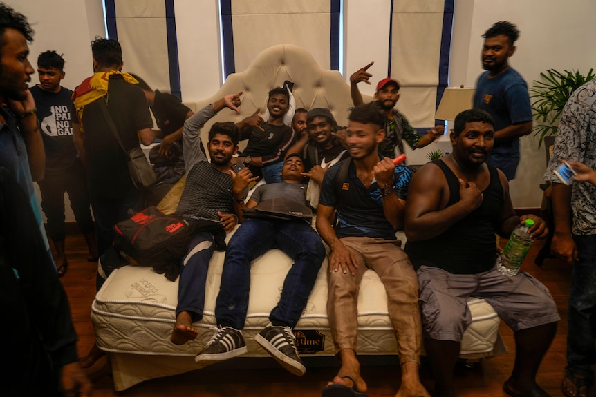 Около дюжины мужчин лежат на кровати в кабинете премьер-министра Шри-Ланки Ранила Викремесингхе, указывая на церемонию.