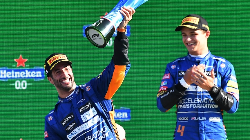 Racing drivers celebrate on the podium.