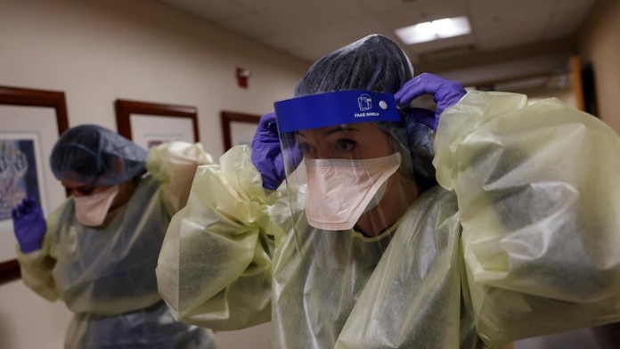 Two healthcare workers put on personal protective equipment