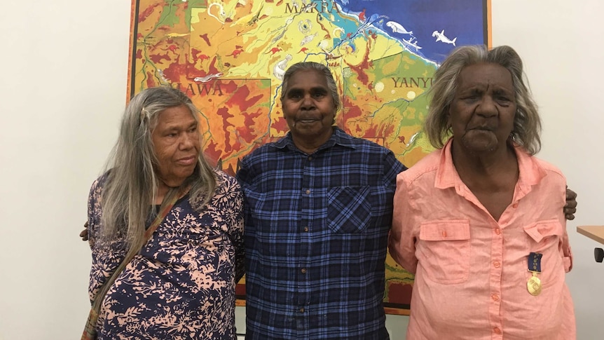 Three women stand in front of a map that shows Marra country and the Gulf of Carpentaria.