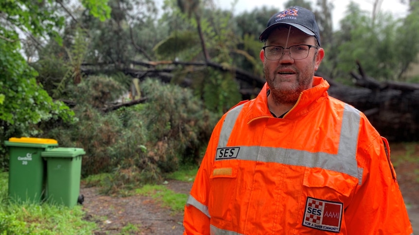 A man wearing glasses and an orange SES jacket.