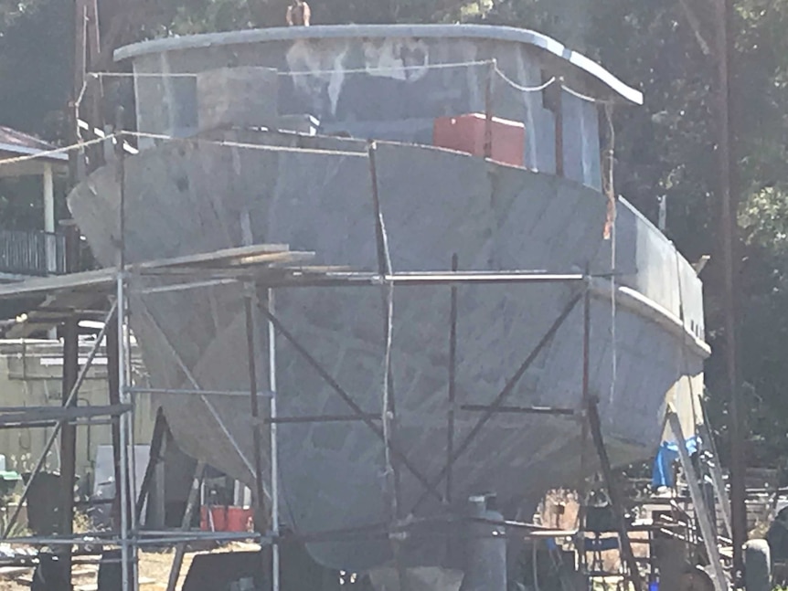A large grey trawler with scaffolding under the bow.