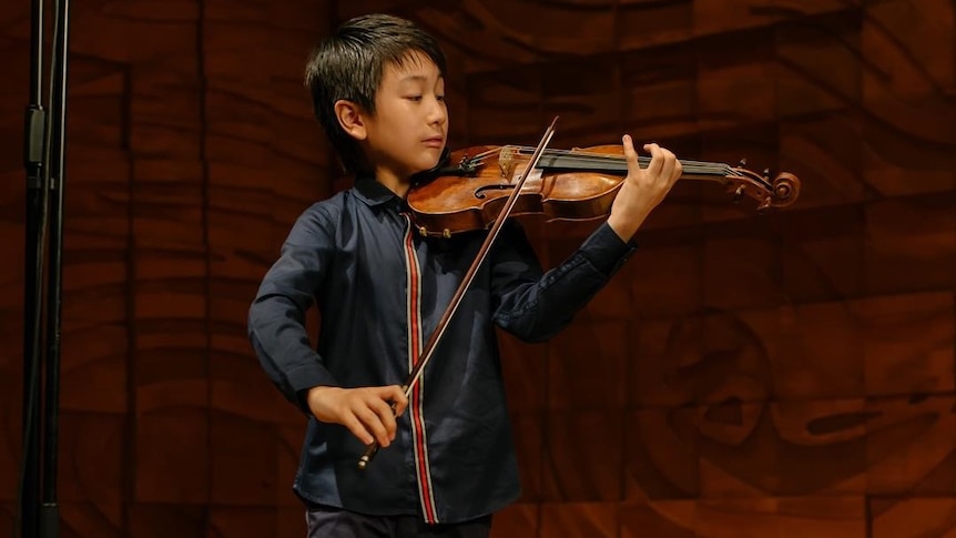 A young boy plays the violin