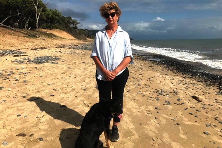 Resident Bronwyn Farr stands on Wangetti Beach with a dog.