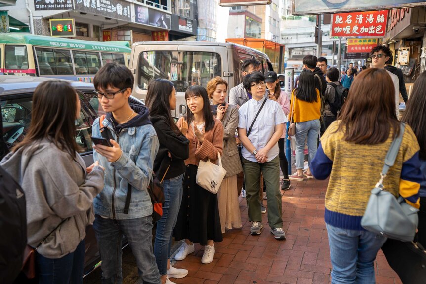 A queue of Hong Kongers on a street outside a restaurant
