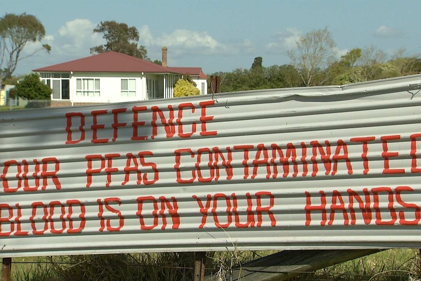 A sign reads "Defence - Our PFAS Contaminated Blood is on your hands"