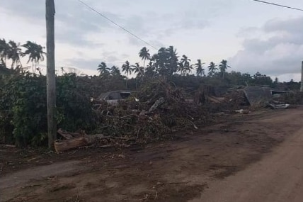 Debris pushed to the side of a dirt road.