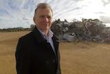 Robert Stewart, Plantagenet CEO, stands in front of a big pile of scrap metal.