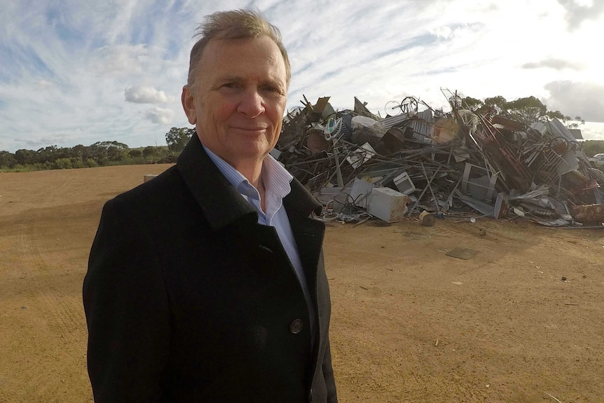 Robert Stewart, Plantagenet CEO, stands in front of a big pile of scrap metal.