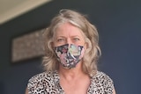 A close-up shot of a woman with a blue and pink floral face mask.