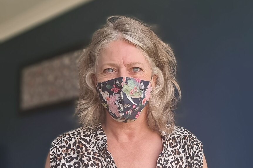 A close-up shot of a woman with a blue and pink floral face mask.