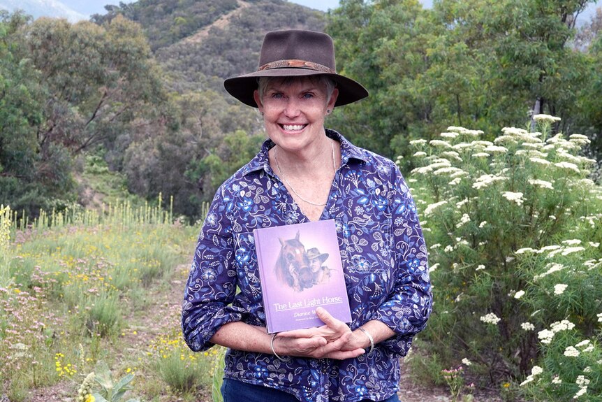 Author Dianne Wolfer holding her latest book, The Last Light Horse