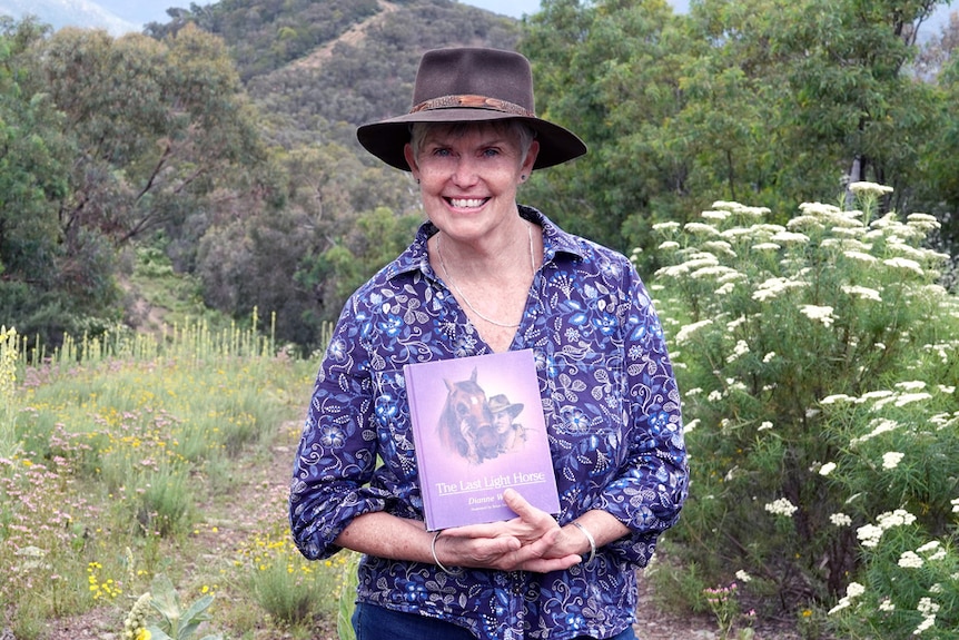 Author Dianne Wolfer holding her latest book, The Last Light Horse