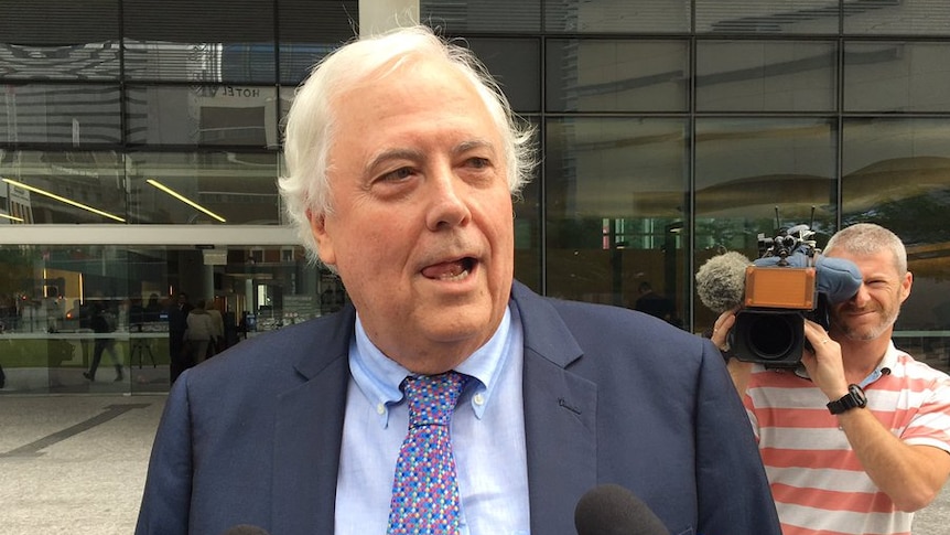 Clive Palmer in a suit speaks to the media outside the Supreme Court in Brisbane.