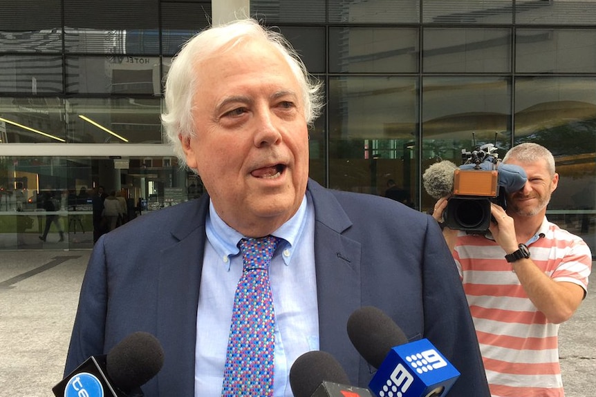 Clive Palmer in a suit speaks to the media outside the Supreme Court in Brisbane.