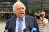 Clive Palmer in a suit speaks to the media outside the Supreme Court in Brisbane.