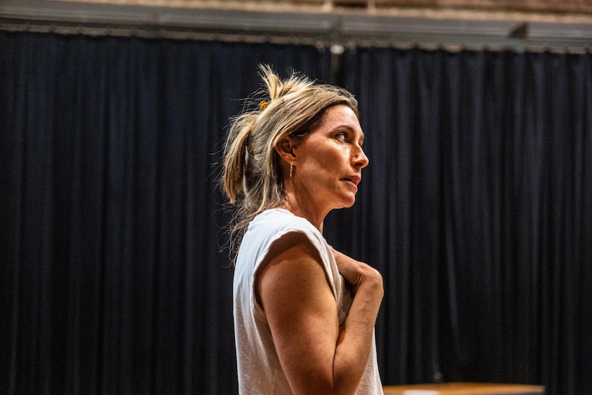 Claudia Karvan wears her hair losely up held by a claw clip and wears a white sleeveless T-shirt.