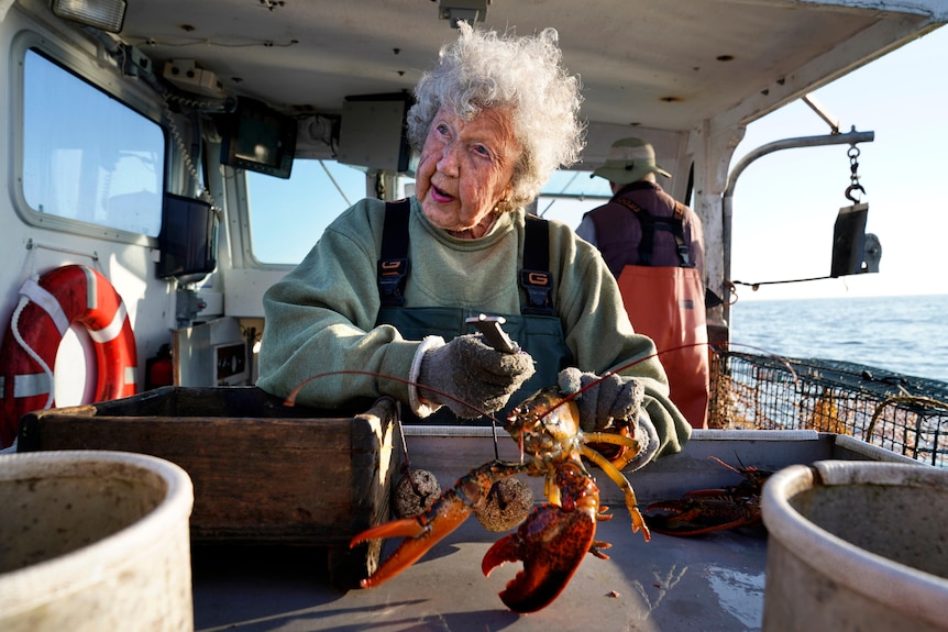 Older woman with a lobster on the back of her boat.