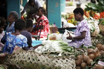 Women shop for fresh food at a street market.