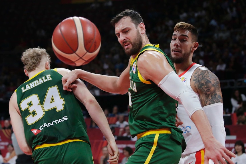 A male basketball players looks to his left as the ball bounces.