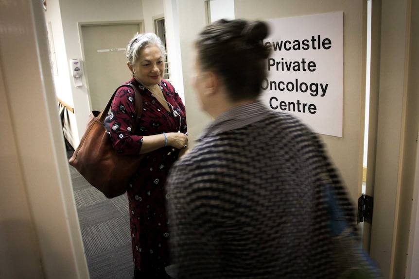A woman smiles as she enters a doctors office.