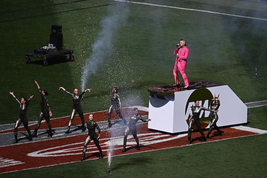 Robbie Williams is ferried across a football ground during a live performance.