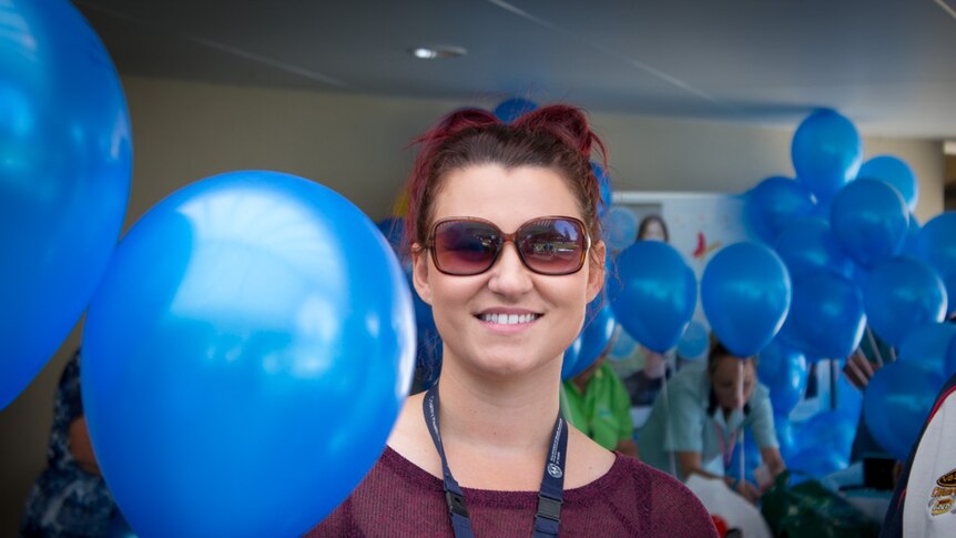Nikea Dymmott holding blue balloons.