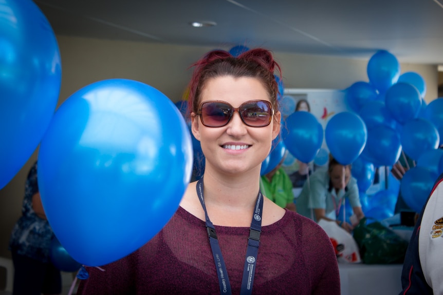 Nikea Dymmott holding blue balloons.