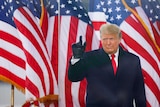 US President Donald Trump stands in front of American flags.