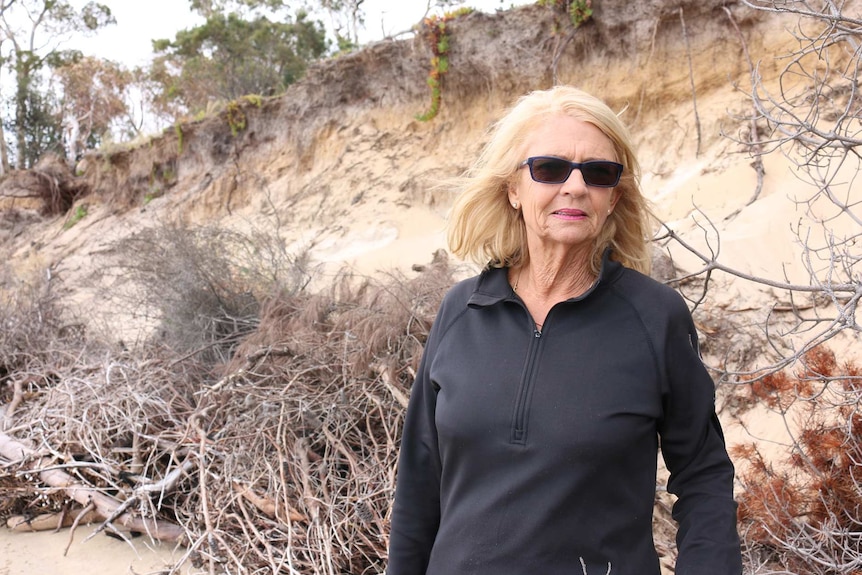 Valerie Reid stands in front of eroded shoreline.