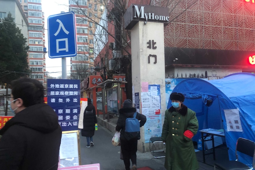 A tent next to a sign with writing in Chinese and a guard in a mask