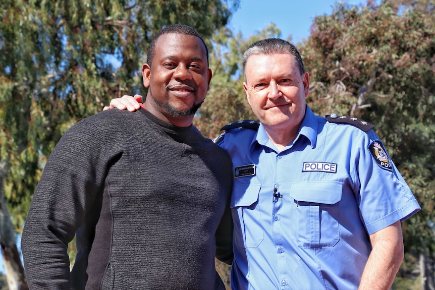 Jo Tuazama stands alongside WA Police Inspector Don Emanuel-Smith outdoors on a sunny day, posing for a photo.