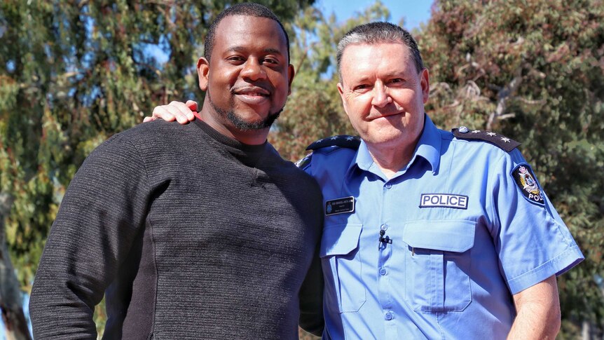 Jo Tuazama stands alongside WA Police Inspector Don Emanuel-Smith outdoors on a sunny day, posing for a photo.