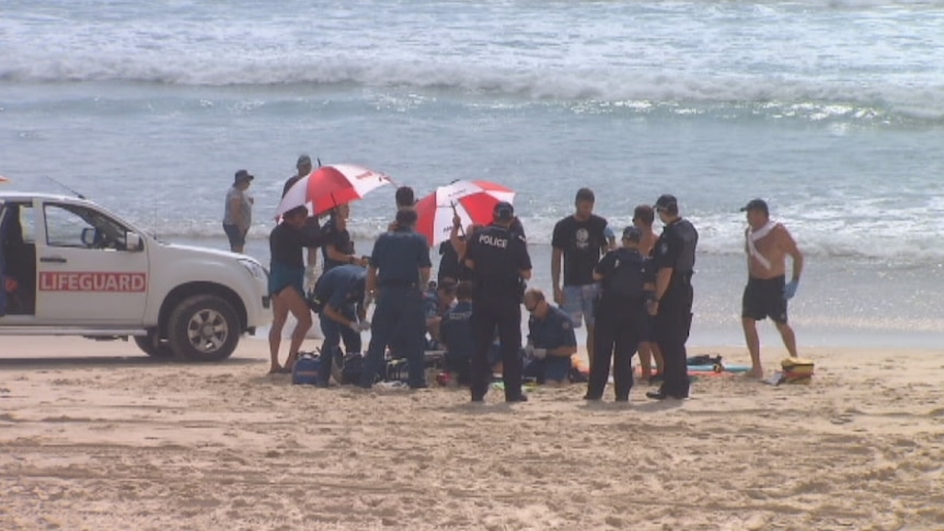 Paramedics attempt to revive a man knocked unconscious after being dumped in powerful surf
