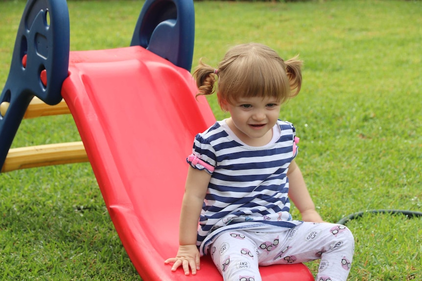 A toddler slides down a kids' slippery slide