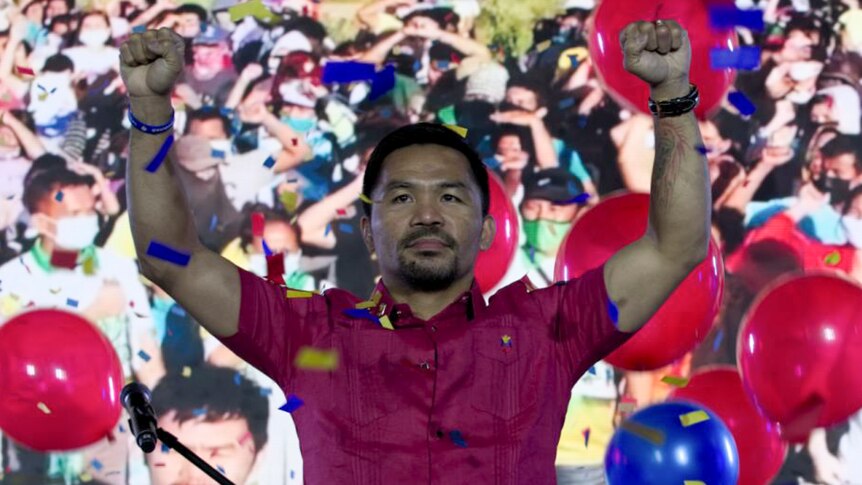 Manny Pacquiao raises his arms triumphantly during a national convention of his party, September 19, 2021.