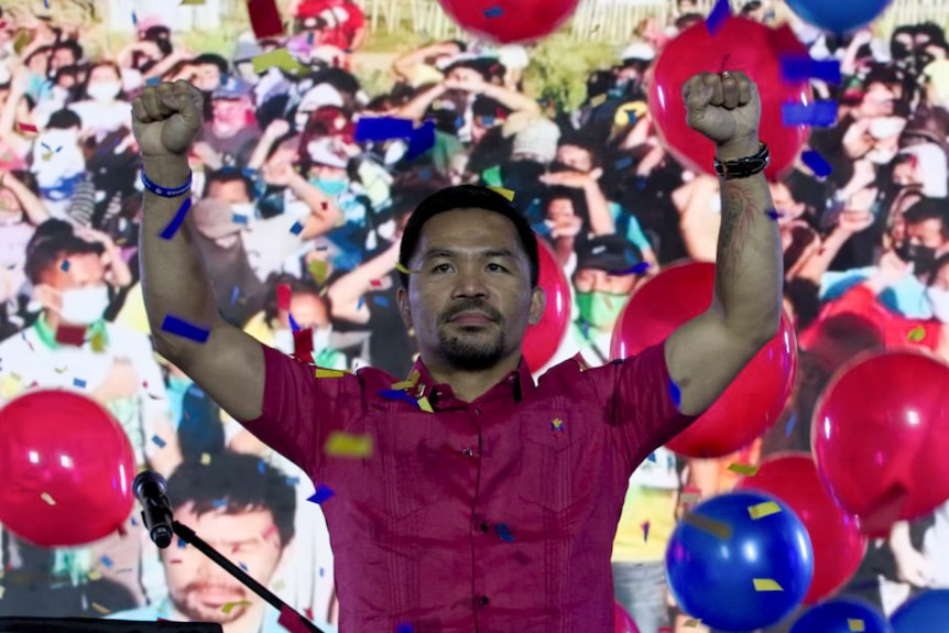 Manny Pacquiao raises his arms triumphantly during a national convention of his party, September 19, 2021.