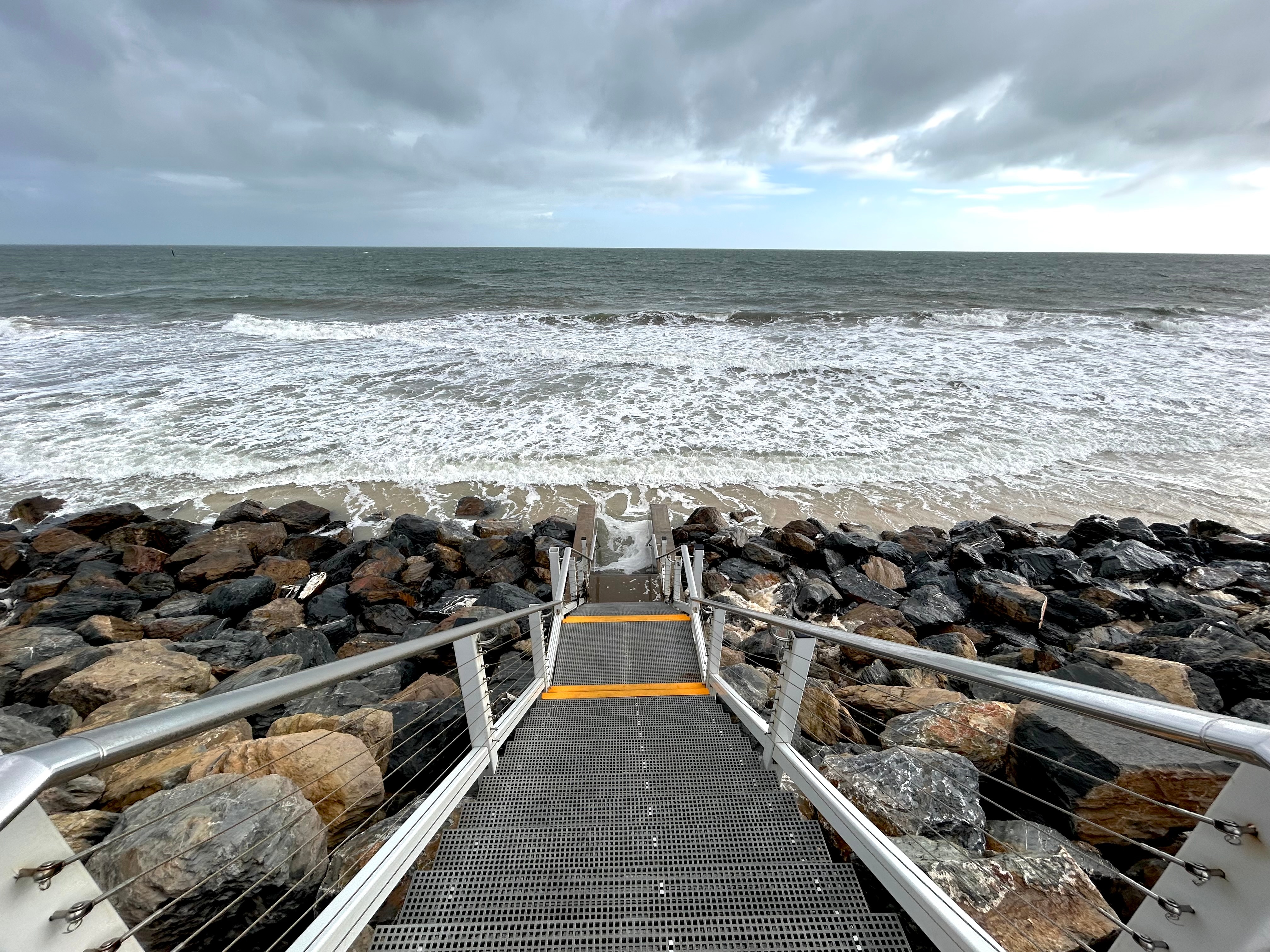 Steps leading down to a beach with a small patch of sand and ocean