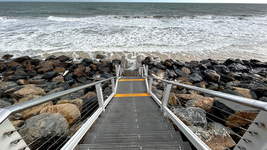 Steps leading down to a beach with a small patch of sand and ocean
