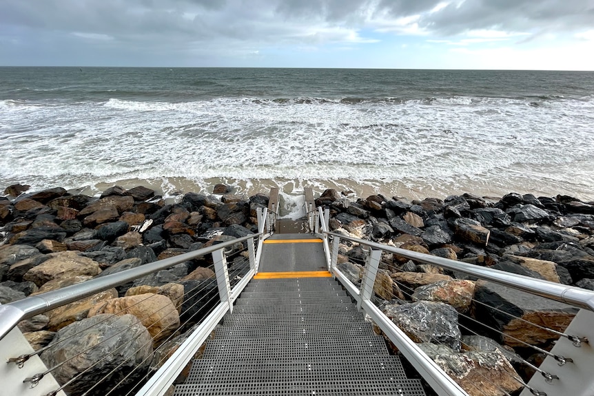 Steps leading down to a beach with a small patch of sand and ocean