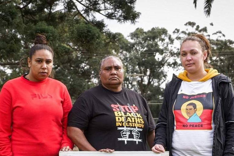 Three Indigenous women hold a portrait of Tane Chatfield