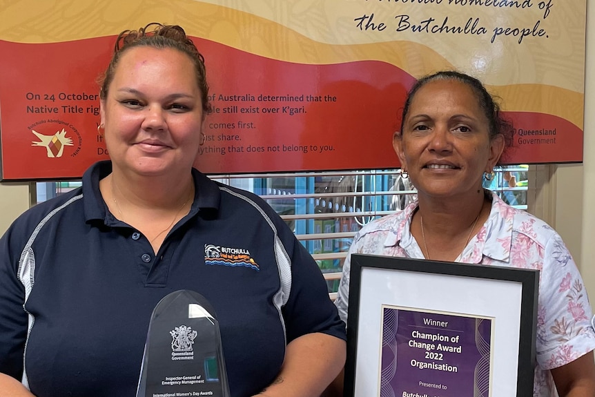 Two women holding a glass award and a framed certificate 